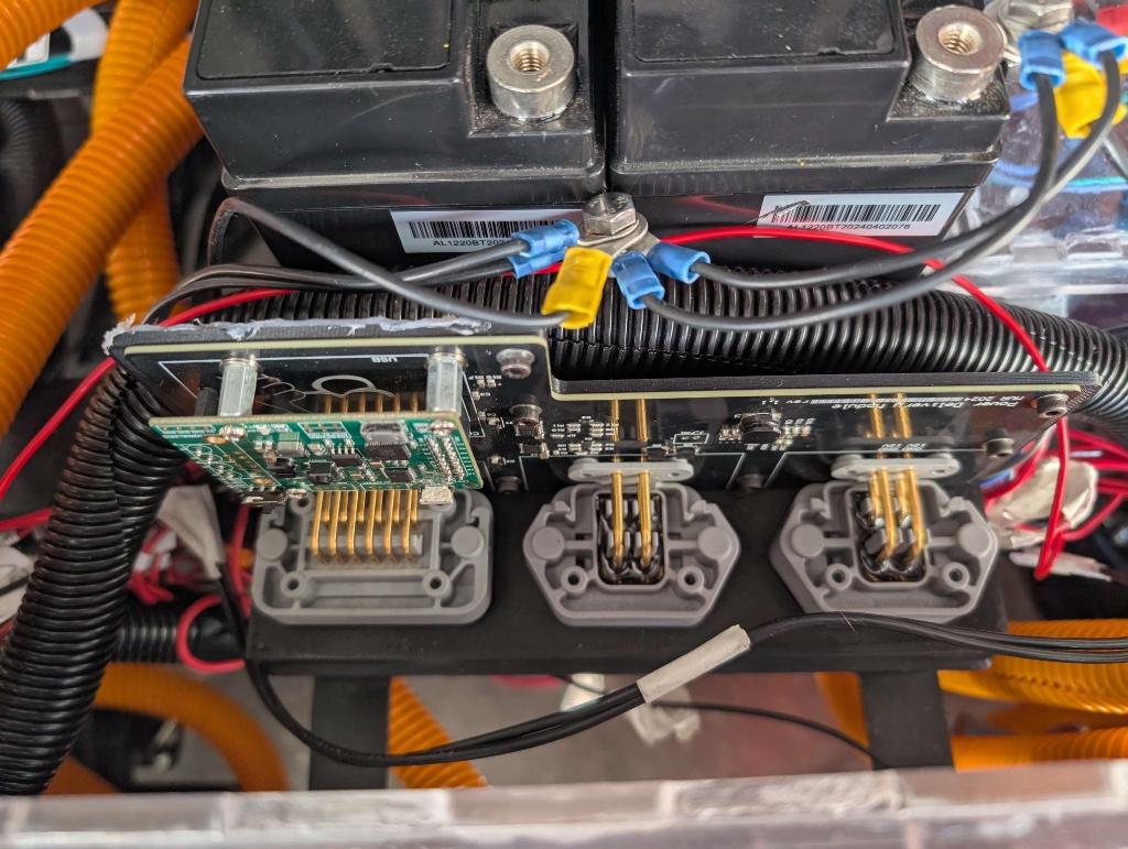 Physical assembly of the PDM installed into the vehicle chassis with wiring harness and batteries